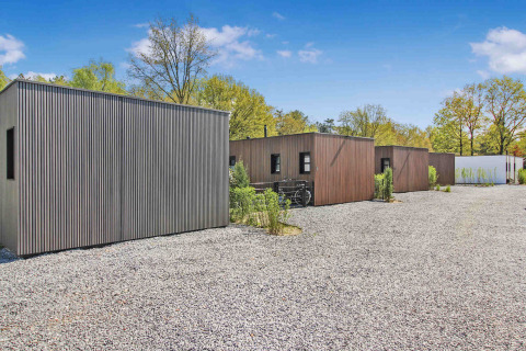 Cabañas modernas en Uniq Leisure, un parque vacacional en Gelderland, Países Bajos, rodeadas de árboles.