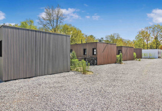 Moderne feriehytter på Uniq Leisure feriepark i Gelderland, Holland, omgivet af natur og blå himmel.