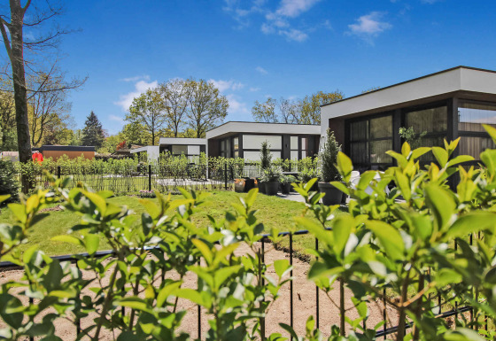 Moderne ferieboliger med grønne haver og blå himmel i Uniq Leisure feriepark, Gelderland, Holland.