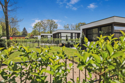 Moderne ferieboliger med grønne haver og blå himmel i Uniq Leisure feriepark, Gelderland, Holland.