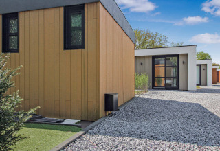 Moderne fritidshus ved Uniq Leisure feriepark i Gelderland, Holland, med træfacader og grussti.