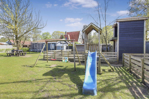 Parque infantil con tobogán, columpios y cabañas de madera en Uniq Leisure, Gelderland, Países Bajos.