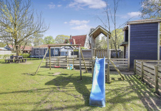 Playground with slide, swings and wooden huts at Uniq Leisure holiday park, Gelderland, Netherlands.