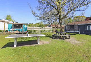 Area esterna di Uniq Leisure, parco vacanze in Gheldria, Paesi Bassi con tavolo da ping pong e trampolino.