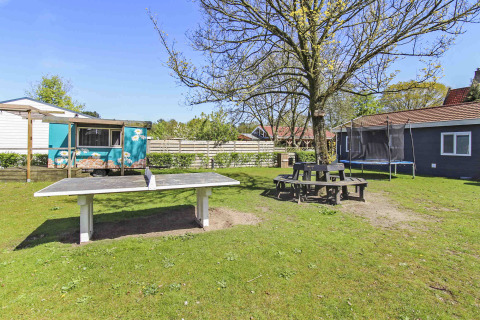 Zona exterior en Uniq Leisure, parque vacacional en Gelderland, Países Bajos con mesa de ping-pong y trampolín.