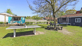 Outdoor area at Uniq Leisure, a holiday park in Gelderland, Netherlands with ping pong table and trampoline.