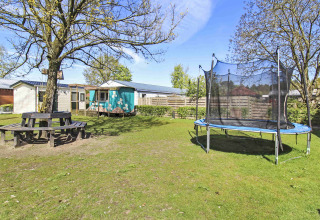Billede af en feriepark i Gelderland, Holland med trampolin, picnicbord og grøn have ved Uniq Leisure.