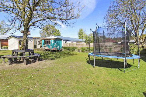 Photo of a holiday park in Gelderland, Netherlands, with trampoline, picnic table, and green yard at Uniq Leisure.