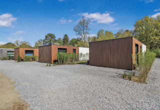 Moderne feriehytter med træfacade på grusplads i Uniq Leisure feriepark, Gelderland, Holland.