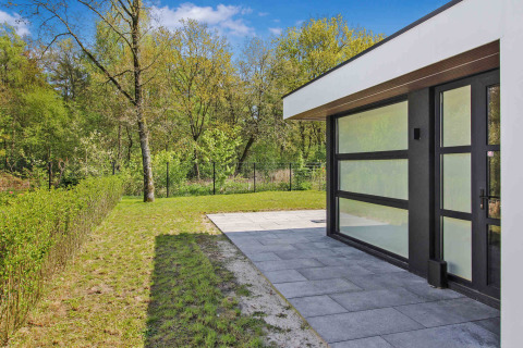 Modern cabin with glass facade and tiled patio at Uniq Leisure holiday park, Gelderland, Netherlands.