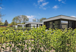 Moderne ferieboliger i Uniq Leisure feriepark, Gelderland, Holland, med grønne haver og blå himmel