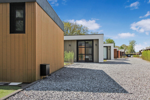 Modernas cabañas vacacionales en Uniq Leisure, parque de vacaciones en Gelderland, Países Bajos con caminos de grava.