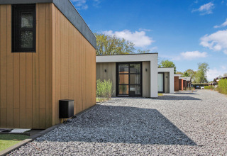 Modern holiday cabins at Uniq Leisure holiday park in Gelderland, Netherlands, with gravel paths and clear skies.