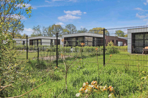Casas de vacaciones modernas en Uniq Leisure en Gelderland, Países Bajos, rodeadas de césped y vallado metálico.