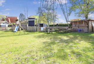 Parque infantil con tobogán, bancos de picnic y cabañas en Uniq Leisure, parque vacacional en Gelderland, Países Bajos.