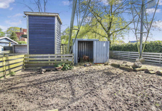 Area esterna recintata con capanni, galline e una capra al parco vacanze Uniq Leisure in Gelderland, Paesi Bassi.
