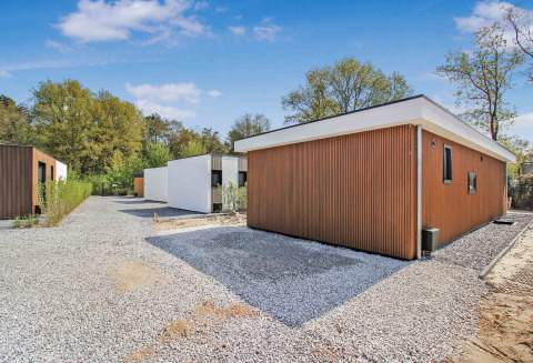 Moderne vakantiehuisjes met houten gevels en grindpaden in Uniq Leisure vakantiepark, Gelderland, Nederland.