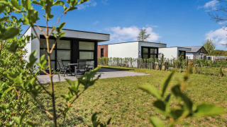 Modern holiday cottages at Uniq Leisure holiday park in Gelderland, Netherlands, surrounded by green lawns.