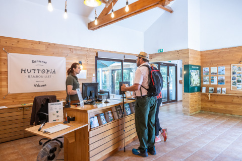 Uomo con zaino parla con la receptionist al parco vacanze Huttopia Rambouillet in Francia.
