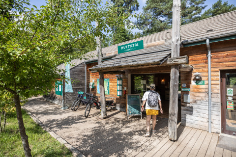 Entrada al parque vacacional Huttopia Rambouillet en Île de France, Francia, con bicicletas y edificio de madera.