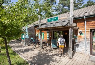 Indgangen til Huttopia Rambouillet feriepark i Île de France, Frankrig, med cykler og træbygning.