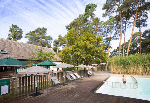 Espace piscine extérieure avec transats et parasols au parc de vacances Huttopia Rambouillet, Île de France, France.