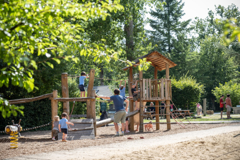 Niños jugando en una estructura de parque infantil de madera en Huttopia Rambouillet, Île de France, Francia.