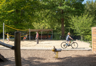 Bambini giocano a pallavolo e vanno in bicicletta al parco soleggiato di Huttopia Rambouillet, Île de France, Francia.