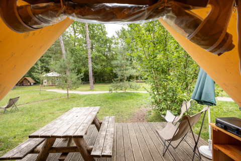 Blick aus einem Canadienne-Safarizelt bei Huttopia Rambouillet, Holztisch und Waldlandschaft.