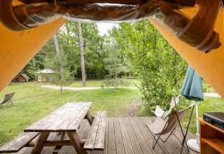 Vista desde una tienda safari Canadienne en Huttopia Rambouillet con mesa de picnic y árboles.