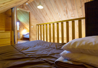 Loft bedroom with wood paneling at The cabin at Huttopia Rambouillet, France, seen from bed view.