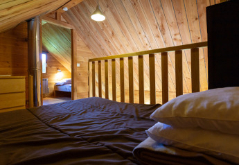 Camera mansardata in legno a The cabin at Huttopia Rambouillet, Francia, vista dal letto.