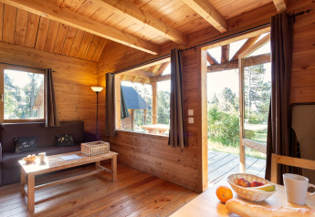 Interno accogliente di una cabina di legno a Huttopia Rambouillet, Francia, con vista sulla natura esterna.