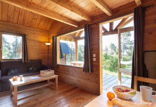 Gemütliche Holzhütte im Huttopia Rambouillet, Frankreich, mit Blick ins Grüne und Holzeinrichtung.