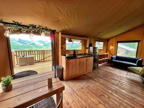 Vista interior de una lujosa tienda safari glamping en Per Amore del Vino, Italia, con cocina y terraza.