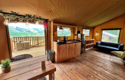 Vista interior de una lujosa tienda safari glamping en Per Amore del Vino, Italia, con cocina y terraza.