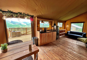 Vista interior de una lujosa tienda safari glamping en Per Amore del Vino, Italia, con cocina y terraza.