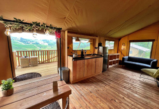 Vista interior de una lujosa tienda safari glamping en Per Amore del Vino, Italia, con cocina y terraza.