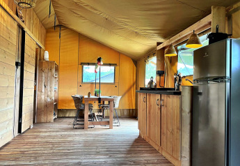 Interior de una tienda glamping con suelo de madera, cocina y mesa en Per Amore del Vino, Italia.