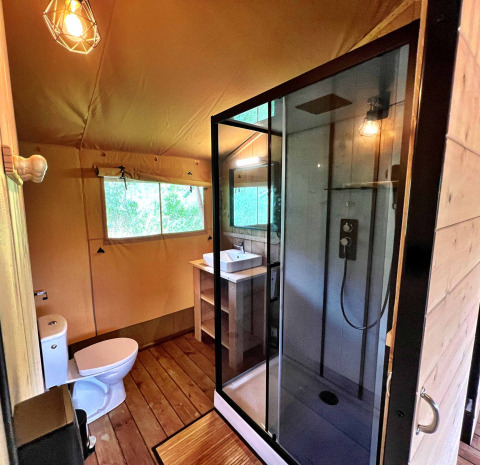 Baño moderno en una tienda glamping safari en Per Amore del Vino, Italia, con ducha y ventana.