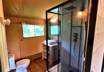 Baño moderno en una tienda glamping safari en Per Amore del Vino, Italia, con ducha y ventana.