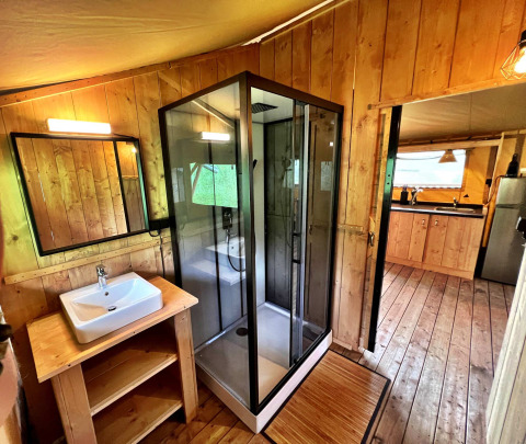 Baño moderno con ducha acristalada en tienda glamping de Per Amore del Vino, Italia, decorado en madera.