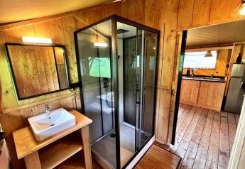 Baño moderno con ducha acristalada en tienda glamping de Per Amore del Vino, Italia, decorado en madera.