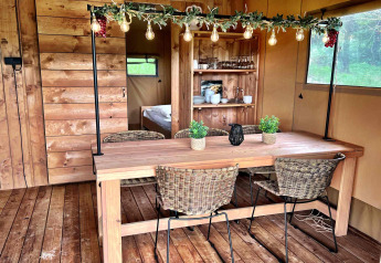 Indoor dining area of a glamping tent at Per Amore del Vino, Italy, with wooden decor and hanging lights.