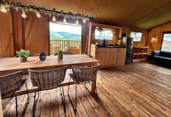 Interior de una tienda glamping de safari de lujo en Per Amore del Vino, Italia, con comedor y cocina.
