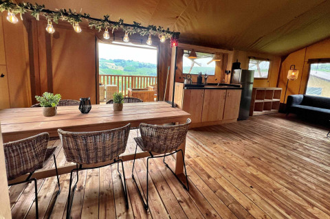 Innenraum eines luxuriösen Glamping-Safarizelts in Italien mit Holzboden, Essbereich und Küche.