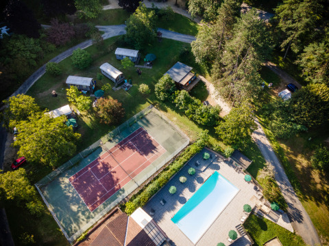 Vista aérea de Huttopia Sarlat en Nouvelle-Aquitaine, Francia, con piscina y pista de tenis.