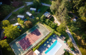 Luftfoto af ferieparken Huttopia Sarlat i Nouvelle-Aquitaine med tennisbane og swimmingpool.