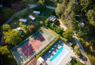 Luchtfoto van vakantiepark Huttopia Sarlat in Nouvelle-Aquitaine met zwembad en tennisbaan.