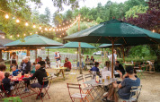 Ambiance de restauration en plein air au Huttopia Sarlat, parc de vacances en Nouvelle-Aquitaine, France, sous guirlandes lumineuses.